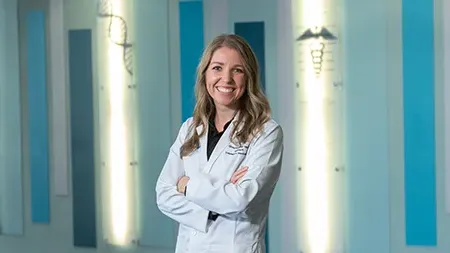 Pharmacy student smiling in white coat.