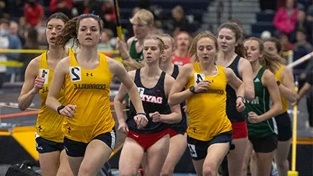 Female track athletes racing on indoor track