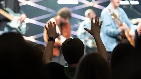 Student raising hands to praise God during chapel service