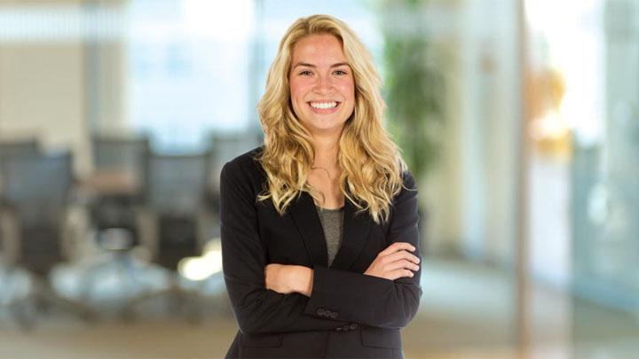 woman smiles at camera with arms crossed in business attire